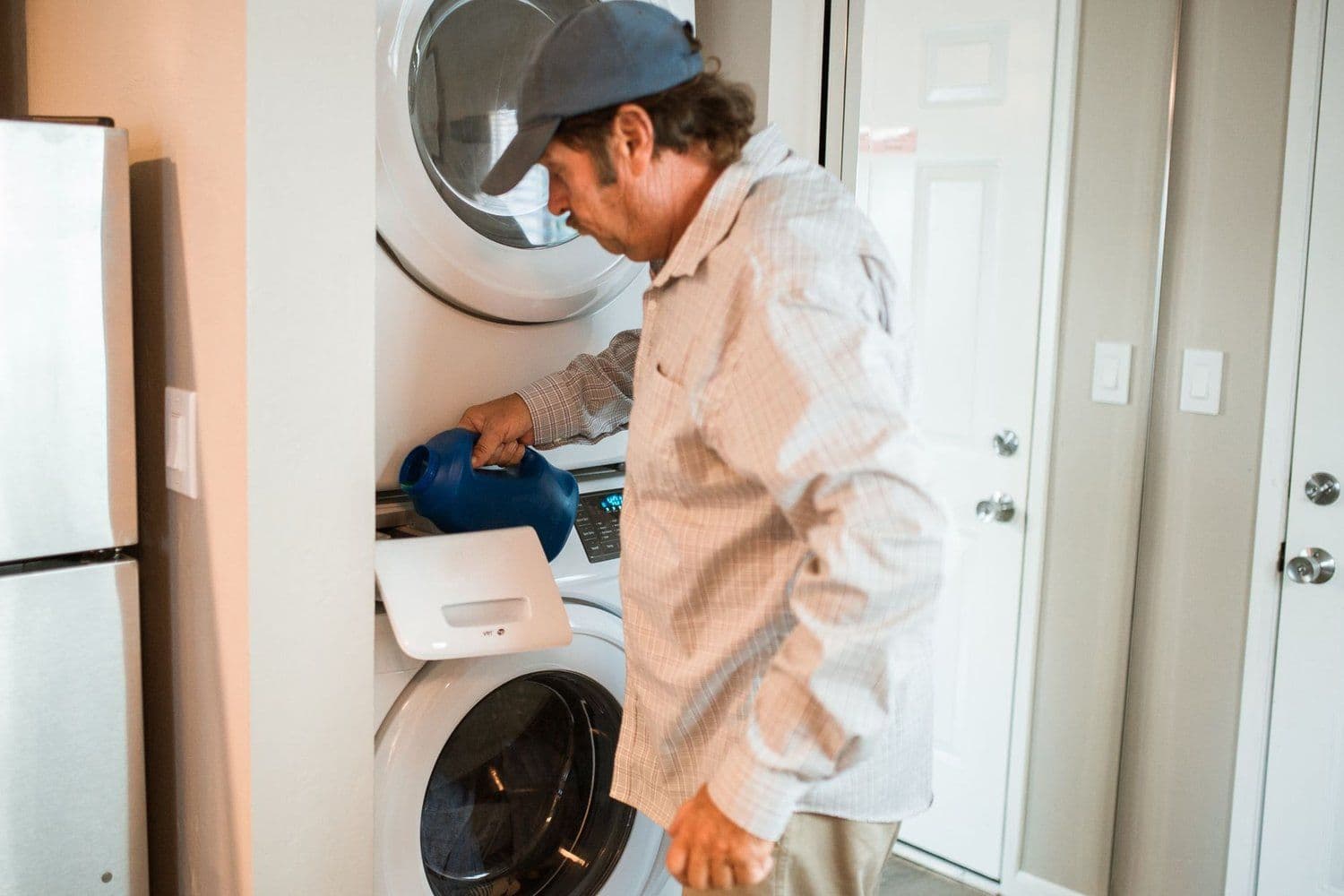 Technician working on a stacked washer and dryer in a home
