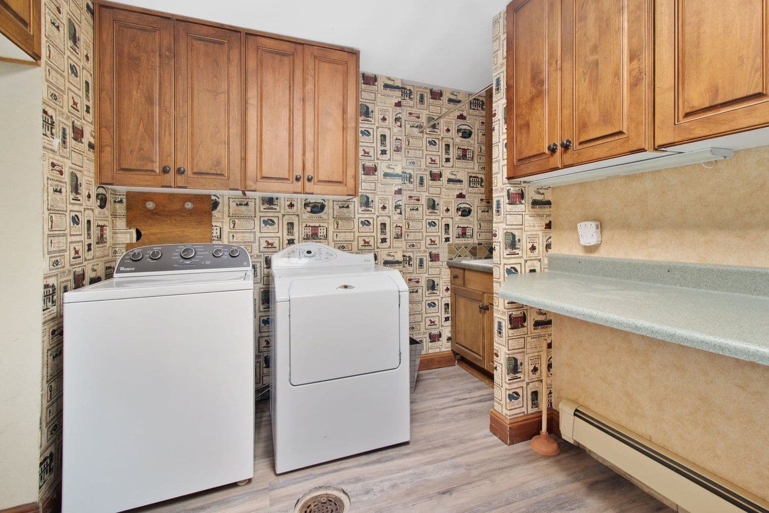 White top-loading washer and dryer side by side in an older laundry room with wooden cabinets